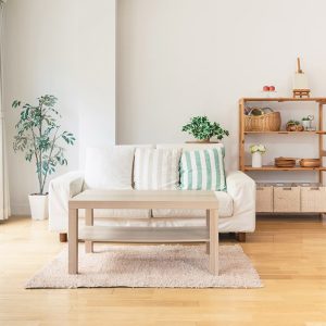 Luminoso salotto in stile nordico, con sofà bianco, grande finestra, tavolino da caffè, scaffale in legno naturale e parquet di colore giallo-dorato