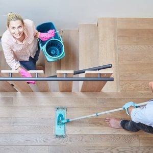 Vita dall'alto su un uomo e una donna che stanno facendo le pulizie, lei guarda nell'obiettivo mentre è sulle scale in legno tenendo il secchio di un