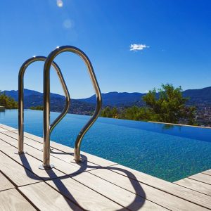 Decking e scaletta di una piscina immersa nella natura con panorama sulle montagne