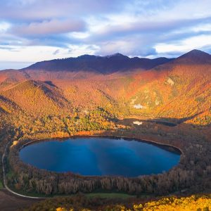 Vista dall'alto di uno dei due laghi di Monticchio, in Basilicata, circondati da montagne e alberi, in autunno