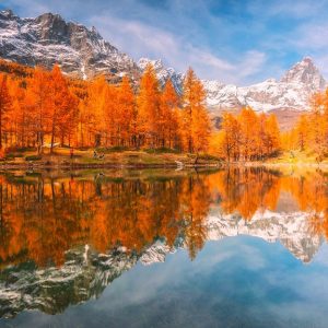 I riflessi degli alberi con le foglie rosse autunnali sul Lago Blu, a Cervinia, con sullo sfondo il monte Cervino