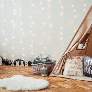 Cameretta dei bambini addobbata per Natale, con parquet, lucine che scendono dalla parete, tepee