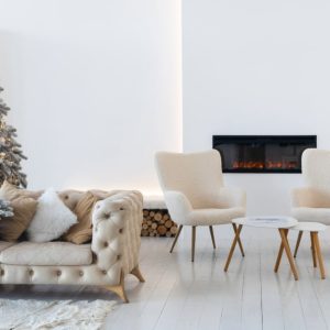 Salotto arredato in stile moderno e minimale, tutto sui toni del bianco, con albero di Natale