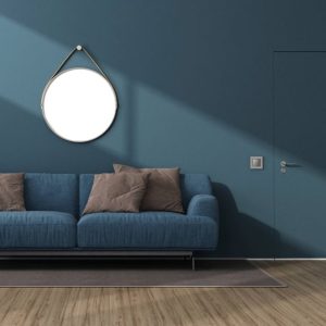 Salotto sui toni del blu scuro, con pareti, porta e sofà dello stesso colore, specchio circolare e parquet