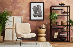 Parquet in rovere in una stanza con pareti marrone-rossicce a effetto limewash e mobili modernisti (sedia, vaso-scultura, libreria nera a giorno)