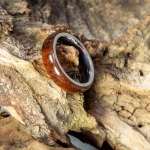 Un braccialetto in legno di cocobolo appoggiato su un pezzo tronco