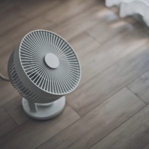 Un ventilatore poggiato su un pavimento in parquet, visto dall'alto